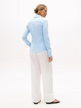 Camisa Tommy Hilfiger de corte slim, confeccionada en piqué de algodón elástico a rayas celestes y blancas, con cuello camisero, cierre de botones y logo bordado en el pecho.