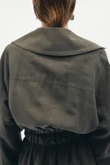 Chaqueta fluida de Zara, con cuello solapa, manga larga ajustable con trabilla y botón, y cinturón del mismo tejido con lazada. Presenta un diseño de corte recto y forro interior a tono.