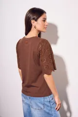 Remera de algodón peinado color negro, con mangas cortas de broderie con diseño calado y terminación festoneada. Presenta un corte oversize y cuello redondo.