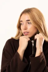 Tapado tipo poncho de color chocolate, confeccionado en tejido de paño, con cierre frontal completo metálico, cuello alto y bolsillos laterales.