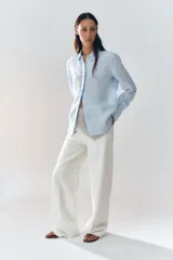 Camisa color coral confeccionada en lino 100%, de corte recto, con cuello solapa, manga larga con puños abotonados y cierre frontal con botones.