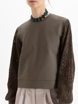 Buzo de calce regular con cuerpo de tela lisa y mangas largas de tejido calado con textura. Presenta escote redondo y puños ajustados.