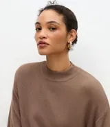 Blusa de punto de corte holgado, color negro, con cuello redondo elevado y mangas cortas amplias con sisa desplazada.