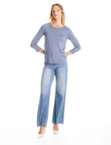 Buzo de tejido fino en color blanco, con cuello redondo y mangas raglán tres cuartos. Presenta una línea de tachas decorativas a lo largo de las mangas.
