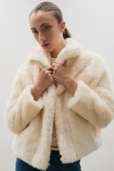 Campera corta de piel sintética en color crema, con cuello amplio tipo solapa y cierre frontal.