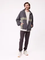 Rompevientos Rusty con cierre frontal, capucha y diseño de bloques de color en gris y verde militar. Cuenta con puños elásticos y logo de la marca en el pecho.