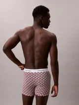 Pack de tres bóxers largos Calvin Klein modelo Icon Cotton Stretch. Incluye un bóxer liso en color rosado claro, uno estampado con patrón geométrico en tonos bordo y blanco, y uno negro liso. Todos cuentan con cintura elástica con el logo de la marca en contraste.