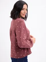 Blusa de algodón color bordó con estampado de lunares claros, cuello mao, cierre frontal con botones y mangas largas.
