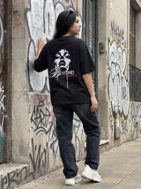 Remera negra de algodón con estampado de rostro femenino y texto "Beyond Limitis" en blanco y rosa.