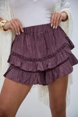 Short pollera violeta con cintura elástica y diseño de volantes escalonados con detalles de encaje bordado.