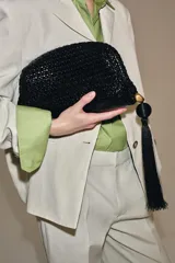 Bolso de mano tipo sobre con diseño trenzado y acabado efecto acharolado. Cuenta con cierre imantado, bolsillo interior con cremallera y detalle de borla lateral con pieza metálica.