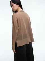 Sweater de tejido fino y semitransparente con hilo brillante. Presenta cuello redondo, hombros caídos y mangas largas amplias con un ajuste relajado y caída fluida.