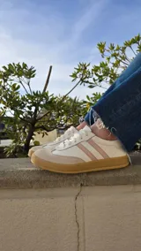 Zapatillas Dallas de cuero blanco, con detalles en gamuza beige y tiras laterales rosadas, suela de goma y diseño urbano.