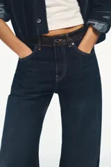 Jeans de tiro alto y pierna ancha con diseño de cinco bolsillos. Presenta una aplicación en la cintura de piel a contraste y cierre frontal con cremallera y botón metálico.