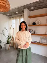 Campera de estilo safari en color beige, confeccionada en material tipo napa. Presenta cuello alto, cierre frontal con botones metálicos, bolsillos frontales con solapa y detalles de trabillas en los puños.