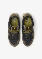 Championes urbanos Satorisan modelo Chacrona Premium, color verde caqui con detalles en negro y marrón. Presentan una entresuela con diseño jaspeado, suela con toques verdes y aplique circular negro en el lateral.