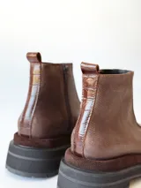 Bota corta de cuero en tonos chocolate, con diseño de paneles texturizados y suela track robusta de goma.