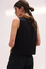 Top sin mangas color blanco con escote en V y volados en el cuello y la botonera delantera.