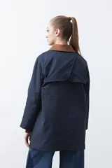 Trench tipo barn jacket color marrón, con cuello camisero en contraste azul marino, cierre frontal con broches y bolsillos amplios. De silueta recta y calce cómodo.