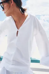 Camisa blanca de la colección ZARA Woman, confeccionada en hilatura con lino, con escote en pico, manga larga con puño ancho y detalles desflecados en cuello y bajo.