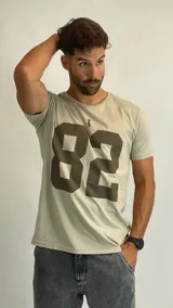Remera de algodón color beige con estampado frontal del número 82 en color marrón y un pequeño detalle gráfico sobre el número.