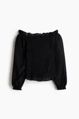 Blusa negra de viscosa con hombros descubiertos, cuerpo fruncido tipo nido de abeja y mangas largas con volumen y puños elásticos.