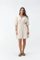Vestido corto beige con escote en V, mangas cortas amplias y cintura elastizada con lazo ajustable.