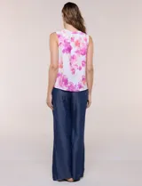 Blusa sin mangas de viscosa blanca con estampado floral en tonos azules, cuello redondo y cierre frontal parcial con botones.