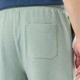 Bermuda de felpa ligera color verde suave, con cintura elástica y bolsillos laterales, de corte cómodo y diseño liso.