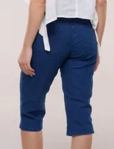 Capri de denim blanco con pretina ancha elastizada, tiro alto, bolsillos simulados al frente y bolsillos funcionales en la parte posterior, con pequeños tajos laterales en el bajo.