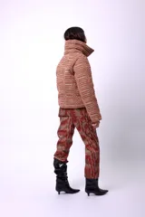 Campera corta con estampado abstracto en tonos marrones y beige, cuello alto, cierre frontal con botones a presión, bolsillos delanteros y bordado negro con las iniciales CP. Forro interior y relleno liviano de guata.