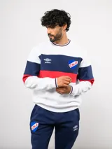 Buzo de cuello redondo confeccionado en felpa, con diseño de bloques de color en azul, rojo y blanco. Presenta el logo de Umbro y el escudo del Club Nacional de Football bordados en el frente.