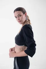 Top negro corto con mangas largas, cuello redondo y detalle de flecos de strass colgantes en el ruedo.