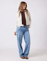 Chaqueta color beige de símil gamuza, con cuello solapa, cierre frontal y bolsillos aplicados en el pecho. Puños con botón a presión.