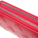 Billetera rectangular de doble compartimento con cierre, color rojo, con diseño de corazones en relieve y logo metálico plateado en el centro.
