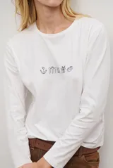Remera de manga larga color blanco, con cuello redondo y diseño de bordado lineal en el centro del pecho que representa elementos de desayuno.