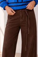 Jean de corte wide leg en color marrón, con tiro medio y cinturón incorporado del mismo tejido.
