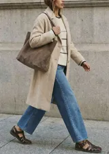 Tapado largo color beige claro, de corte oversize, con cuello solapa y cierre frontal de botones.