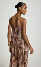 Blusa de tul sin mangas, con escote en V, tirantes finos y estampado orgánico en tonos marrón y beige. Presenta diseño fluido, suave transparencia, bajo asimétrico con puntas alargadas y corte recto.