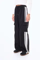 Pantalón cargo de corte amplio, color negro, con franjas laterales blancas y bolsillos tipo cargo en los costados. Presenta cintura elástica con cordón ajustable.