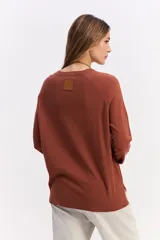 Sweater de punto negro con cuello redondo, manga larga y calce relajado. Presenta una costura vertical central en el frente y puños acanalados.