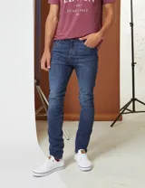 Jean de corte slim en color azul medio, con diseño clásico de cinco bolsillos y cierre frontal con botón y cremallera.