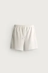 Bermuda jogger relaxed fit confeccionada en tejido interlock de algodón con elasticidad, de color beige, con cintura elástica ajustable con cordón y bolsillos.