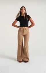 Pantalón de jean color tostado, de corte wide leg con tiro alto y cierre frontal con botón metálico. Presenta un diseño de cinco bolsillos y ruedo desflecado.