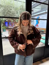 Campera reversible de corte holgado con cuello alto. De un lado presenta un diseño a cuadros en tonos marrones y beige, y del otro lado un diseño liso. Cuenta con cierre frontal de botones y mangas largas.