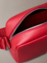 Bolso bandolera rojo de cuero sintético con monograma CK grabado en el frente y correa ajustable con el logo de Calvin Klein.