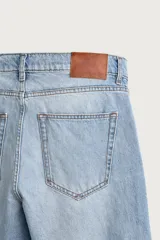 Pantalón de jean corte slim fit, color azul oscuro, con diseño de cinco bolsillos, tiro medio y cierre frontal con cremallera y botón.