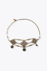 Cinturón de múltiples cadenas metálicas en tonos dorado envejecido y plateado. Presenta secciones de malla con diseño de rombos y dijes colgantes con grabados oscurecidos.