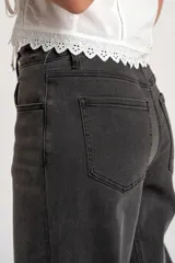 Jean de corte baggy con tiro medio, confeccionado en denim de color gris lavado. Presenta un diseño de pierna ancha con costuras horizontales a la altura de la rodilla y cierre frontal con botón y cremallera.