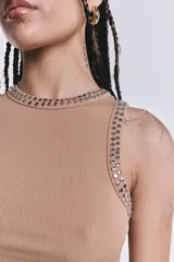 Musculosa camel de tejido rib, al cuerpo, con detalles de tachas metálicas aplicadas en el cuello y las sisas.